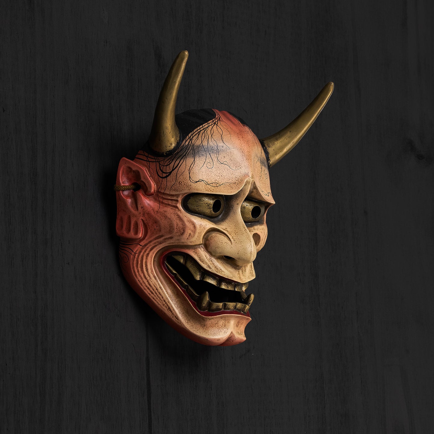 White Traditional Hannya Mask mounted on a black wall