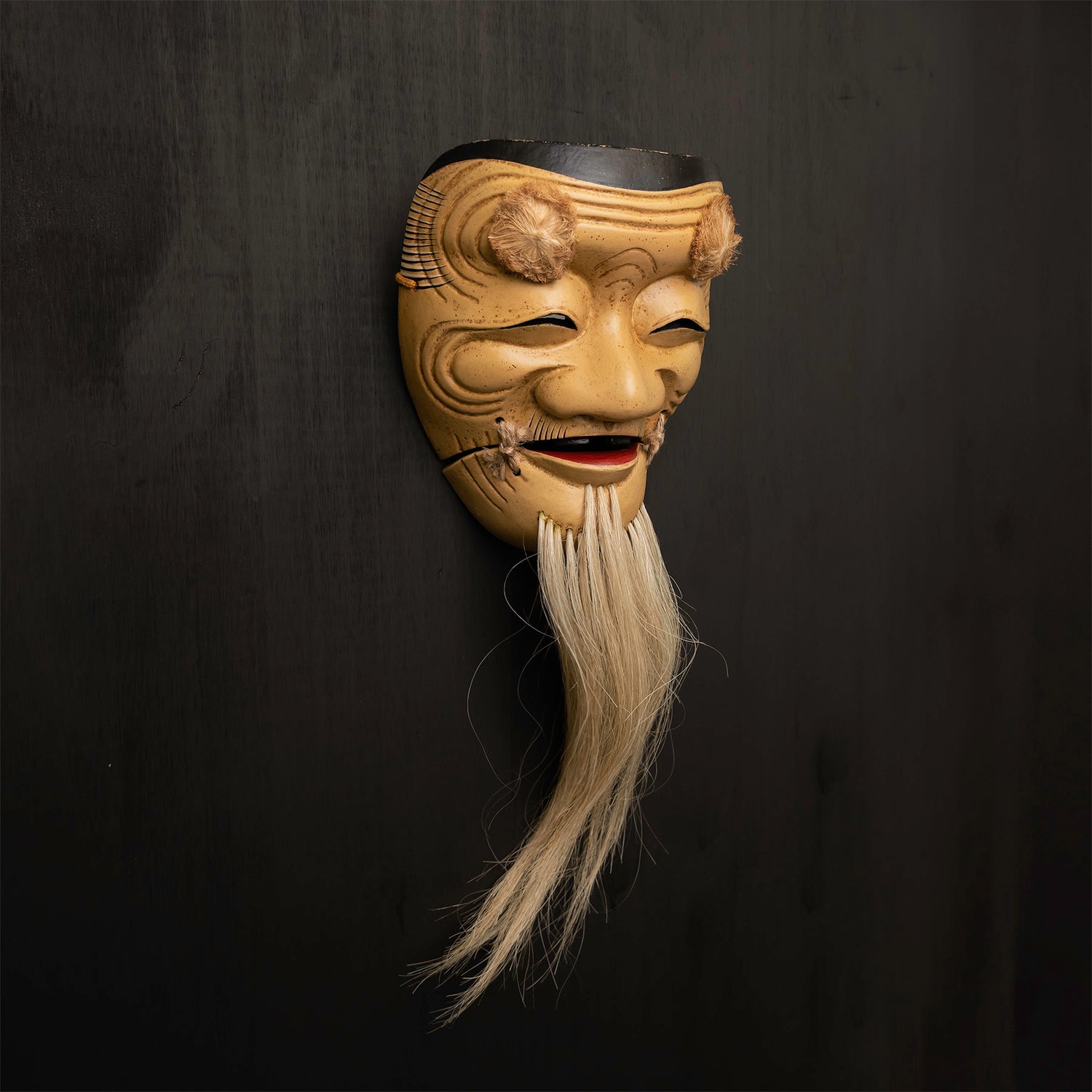 Okina Mask mounted on a black wall